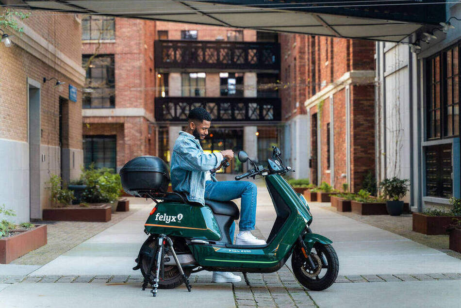 Spring Campaign — fotograaf zittend op de Felyx-deelscooter tussen de baksteenarchitectuur