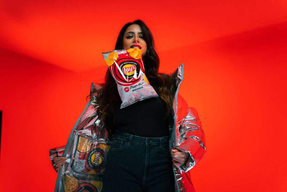 Lay's Iconic Restaurant Flavours — model houdt een zak Lay's omhoog tegen een dieprode achtergrond