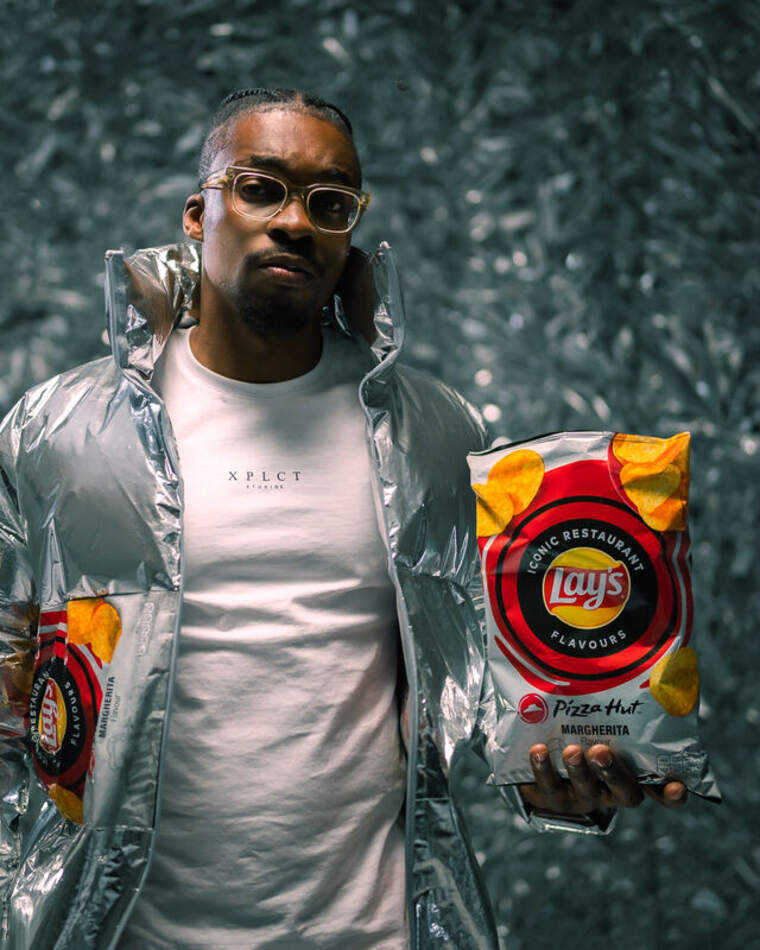 Lay's campagne — model houdt een zak Lay's Pizza Hut richting de camera op de foliewand-set