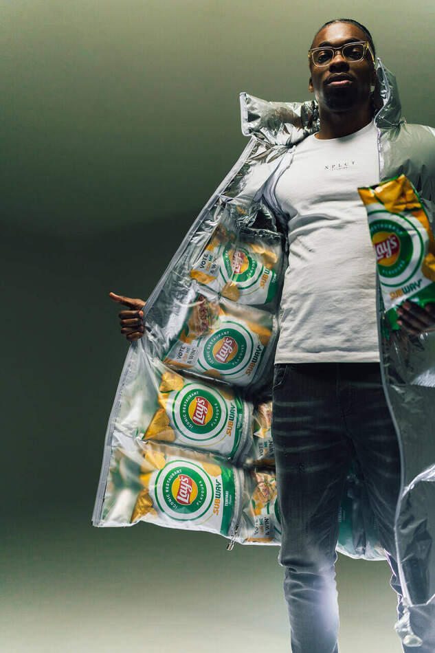Lay's campagne — model ten voeten uit met de pufferjack open, gevoerd met Lay's Subway-zakken