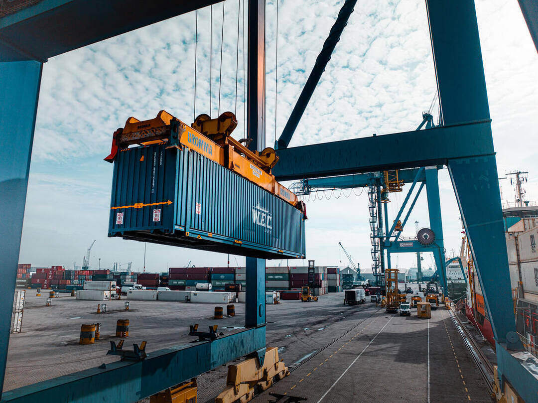 Dronefoto — de kraan zet een container op de trailer aan de kade