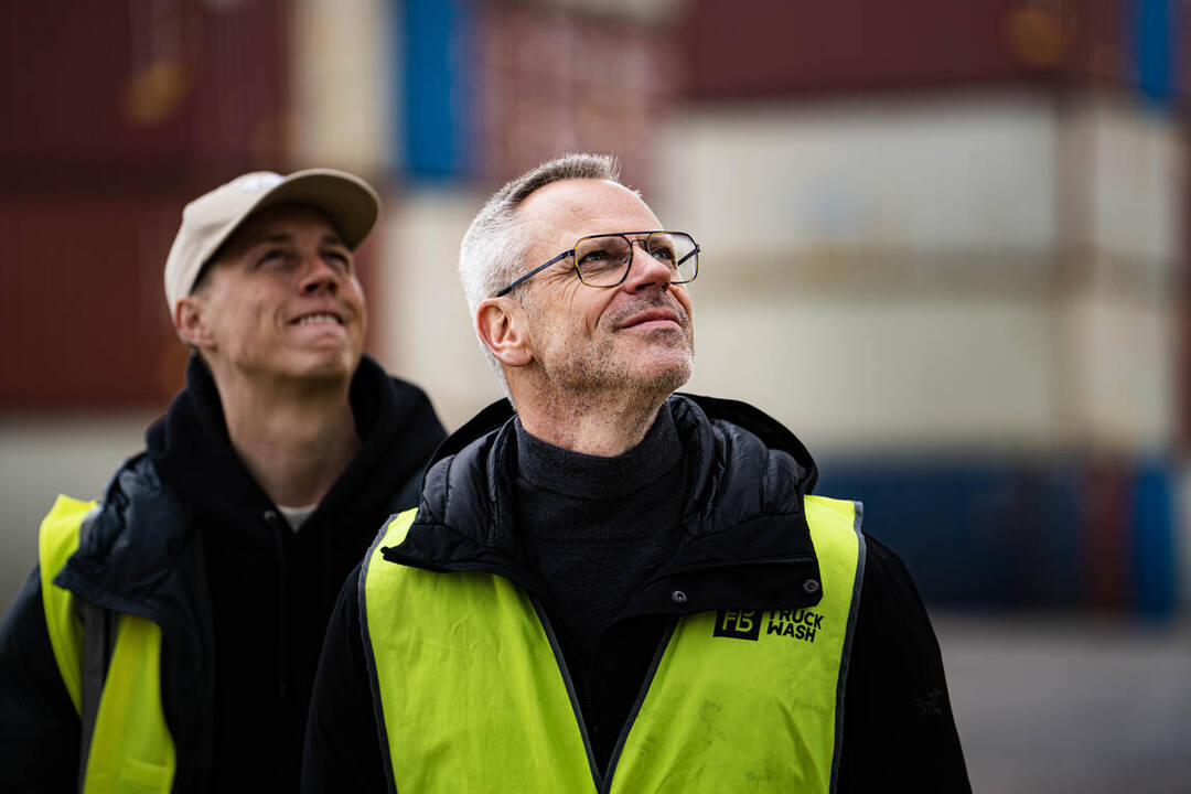 Twee medewerkers volgen het lossen van het schip op de kade