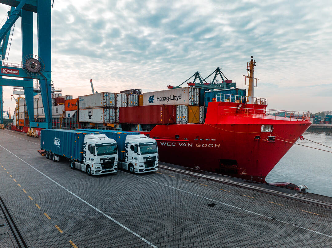 Dronefoto — twee WEC-vrachtwagens naast het schip aan de kade